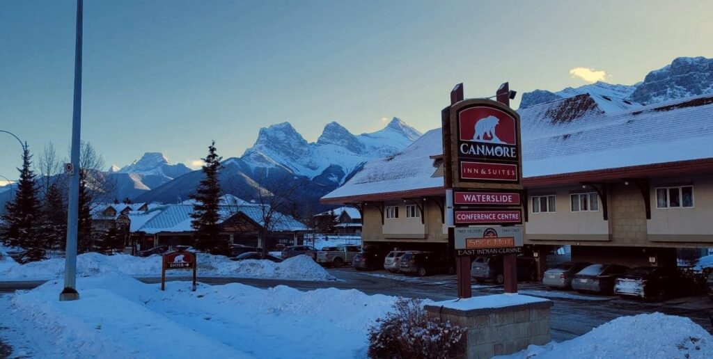 Exterior of the Canmore Inn + Suites with the Three Sisters mountains in the background