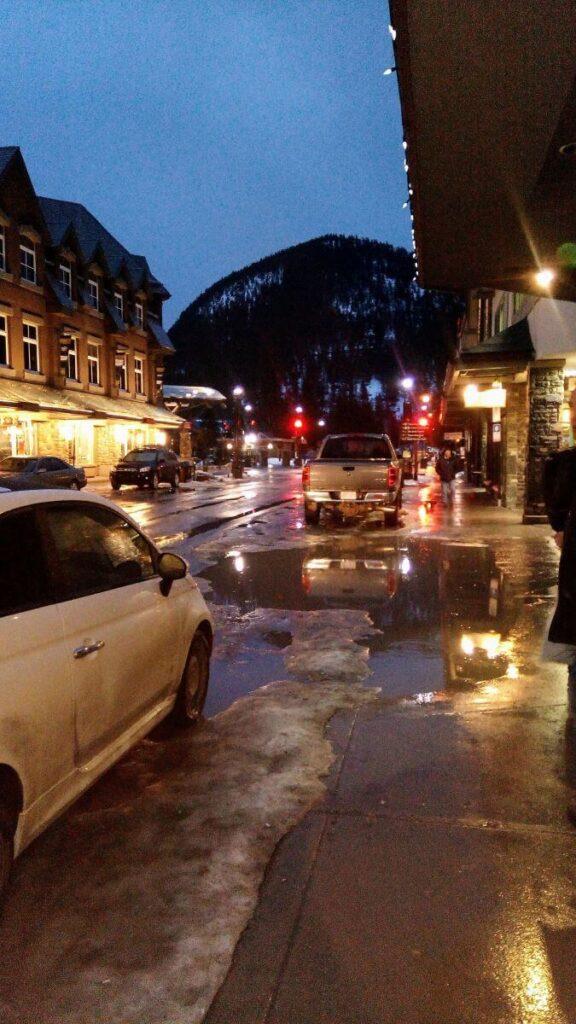Late evening in downtown Banff in March with melting and slushy snow on the ground.